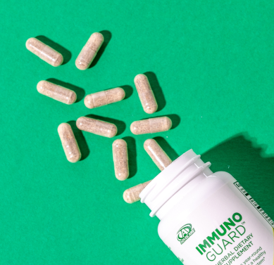 A open bottle of ImmunoGuard on it's side with capsules spilled out from its opening.