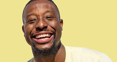 Man smiling set against a yellow background.