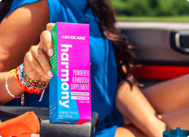 A woman sitting in the drivers seat of a car showing off a box of Harmony.