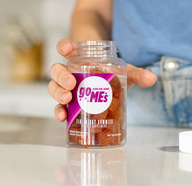 A person's hand wrapped around an open GO MEs Elderberry bottle