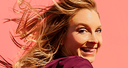 Woman smiling against a pink background.