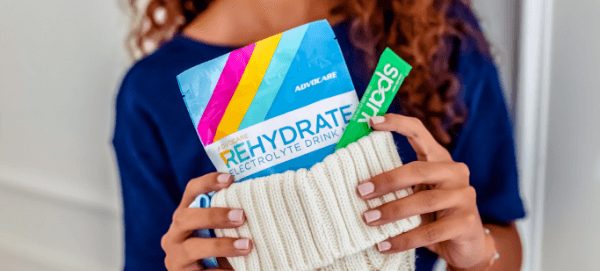 A woman holding a white stocking with a Rehydrate Sample Pack inside of it