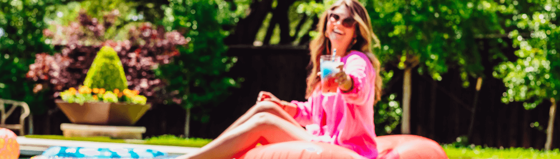 A woman at the pool holding up a glass of swirled Spark and Rehydrate.
