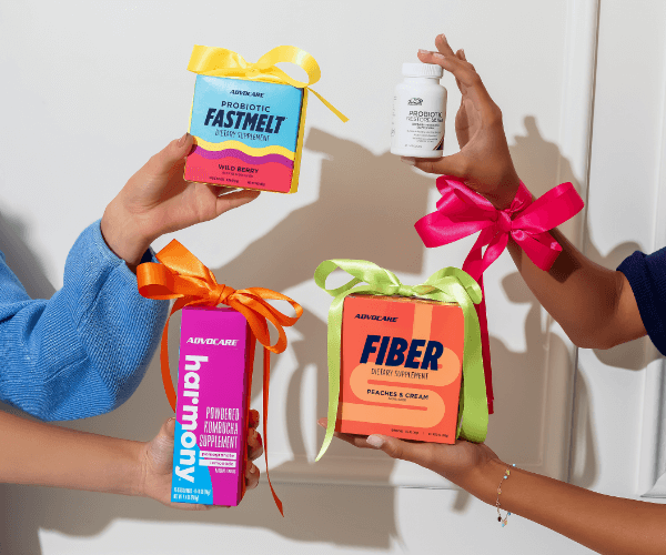 Probiotic FastMelt®, AdvoCare Harmony™, Probiotic Restore Ultra®, and AdvoCare® Fiber all being held up in front of a white wall