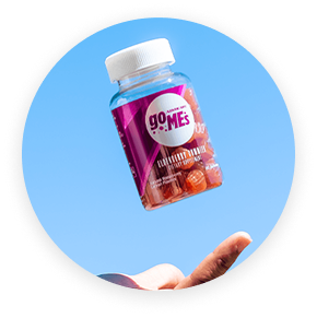 A hand catching a a bottle of GoMes Multivitamin against a blue sky background.