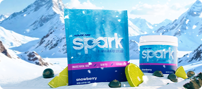 AdvoCare Spark Snowberry Gusset Bag and Canister sitting on a snowy mountain with lime slices and currants scattered around.