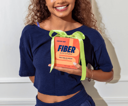 A young woman holding up a box of Probiotic FastMelt® wrapped with a yellow bow