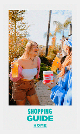 Two women holding a glass bottle of Rehydrate in a backyard. Shopping Guide Home.