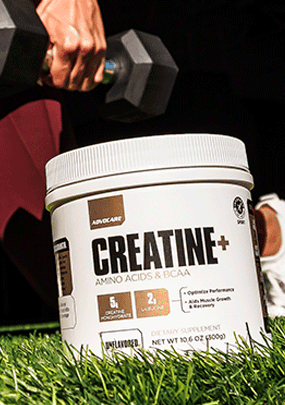 Creatine+ sitting on a grass field in front of a person working out with free weights.