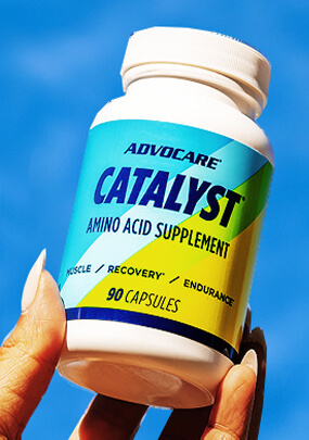 A hand holding up a bottle of AdvoCare Catalyst.