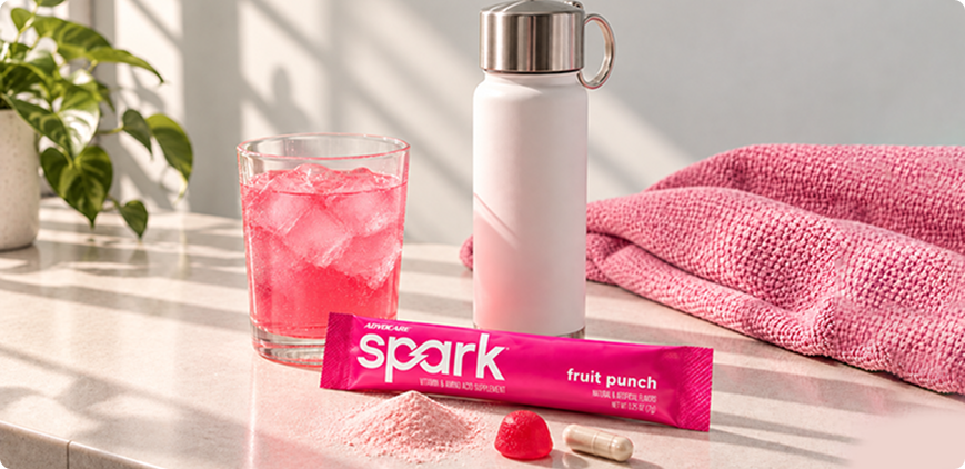 Spark Fruit Punch stick pack on a counter with a glass and sports bottle.