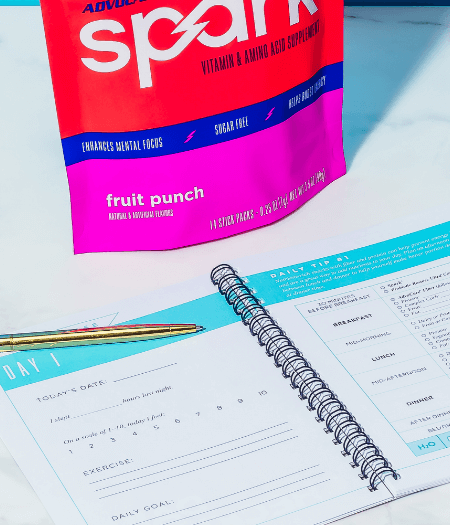 An open 24-Day JumpStart workbook with a Spark gusset bag above it