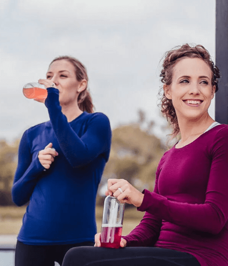 Two athletic women at the park drinking Spark